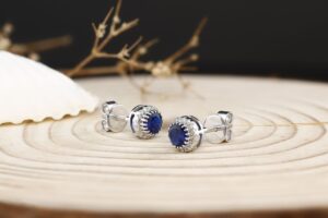 Close-up of sapphire stud earrings with silver and diamonds.